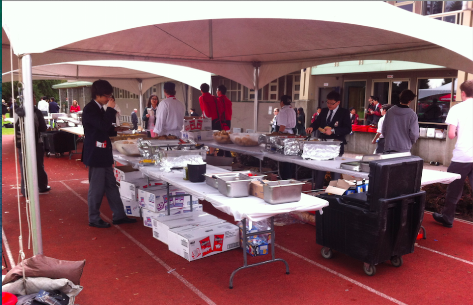 Students obtain their hot dogs and hamburgers under the tent.