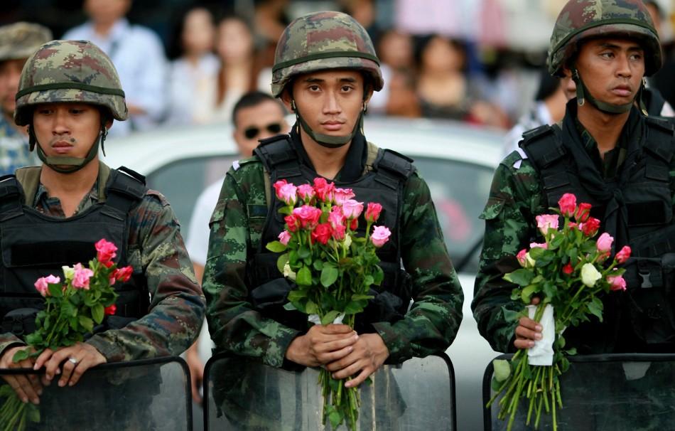 Soldiers holding flowers given to them by protesters.
