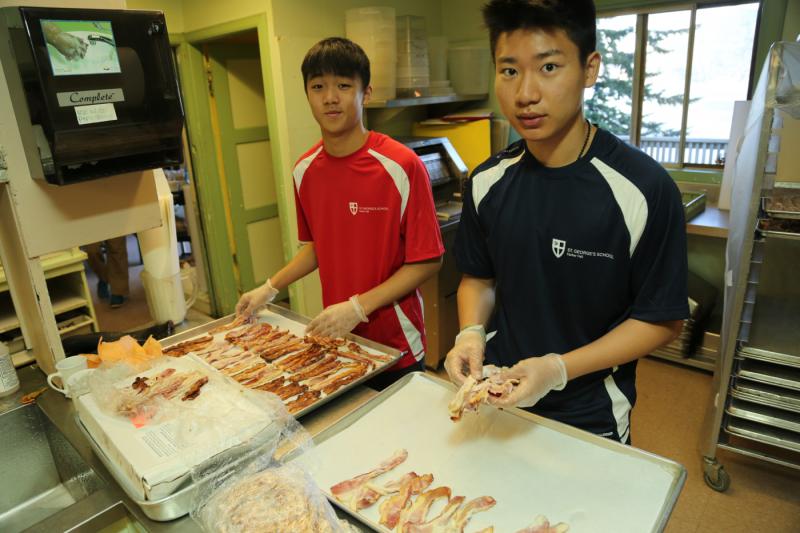 Two students helping prepare breakfast.