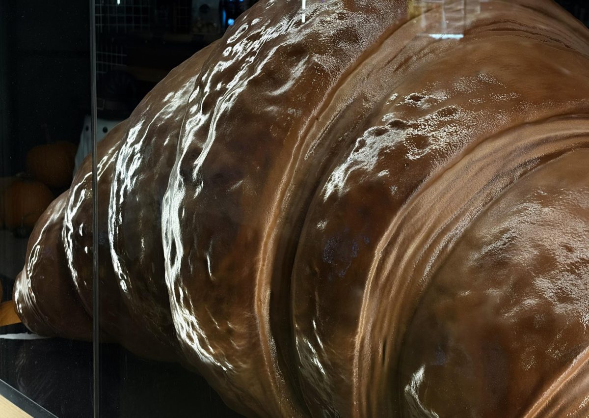 Bisou Bakehouse’s large croissant display sitting behind glass, illuminated by vibrant city lights.