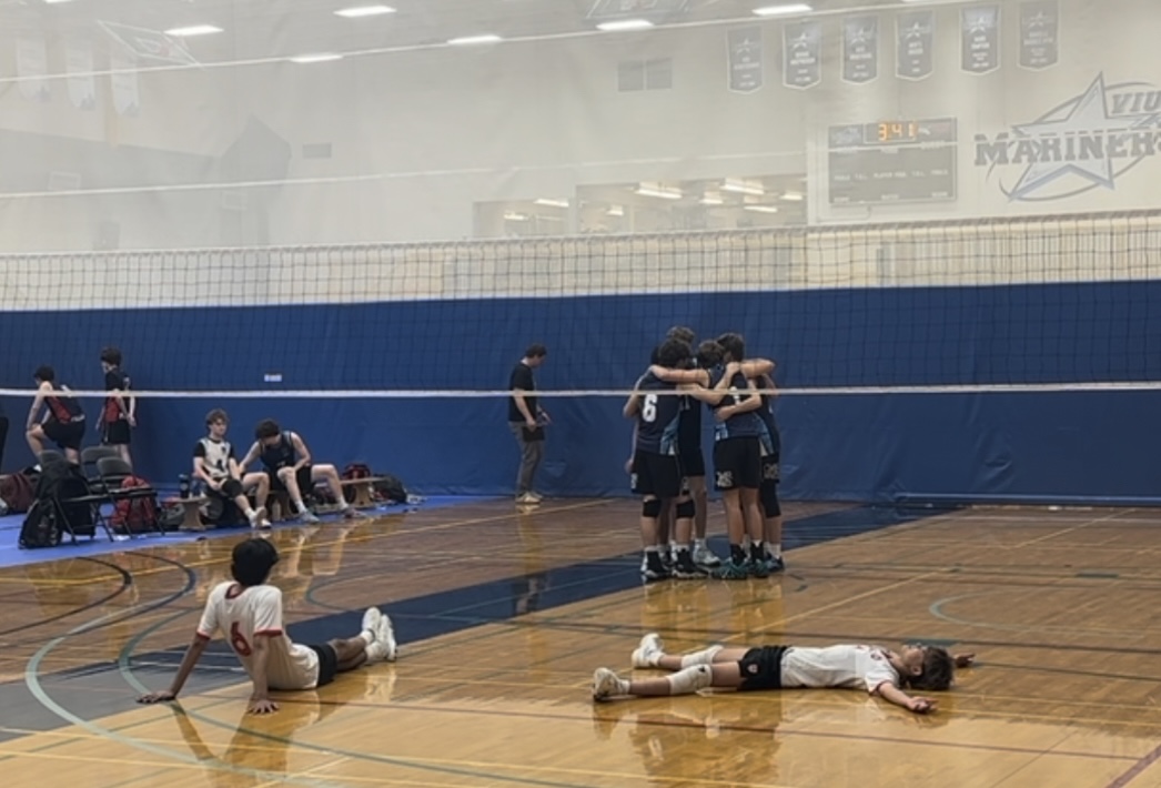 An exhausted St. George’s team resting on the gym floor during a timeout.